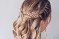 a boho wedding half updo on medium hair, with a large fishtail braid on one side and waves down is a stylish solution