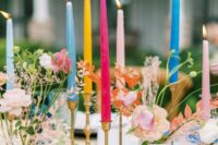 a bright eclectic wedding centerpiece of colorful candles and blush blooms and greenery is a cool and fun idea for a wedding