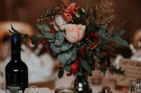 a chic eclectic wedding centerpiece of a tree slice, mercury glass candleholders and a sugar pot, a bright floral arrangement in a bottle, a cardboard table number