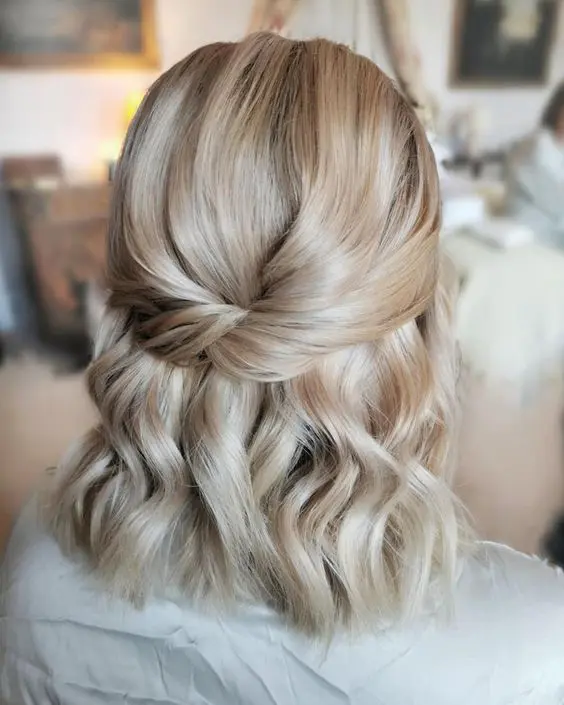 a cold blonde half updo with a twisted top and waves down is a chic and creative idea that looks elegant