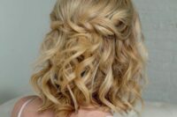 a curly half updo with a twisted braid and curls down plus a peachy crystal crown are a cool combo