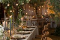 a fabulous indoor enchanted forest wedding reception space wiht trees and colored candles on the tables, some hanging candles and neutral linens