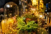 a fairy woodland wedding centerpiece with cloches with lights, moss, greenery and succulents is a gorgeous idea for your enchanted forest celebration