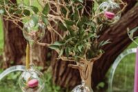 a fantastic enchanted forest wedding centerpiece of a tree with greenery and a moss base, bubbles with pink macarons is amazing