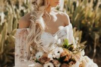 a gorgeous boho bridal hairstyle with a braided halo and a loose fishtail side braid plus a chamomile headband