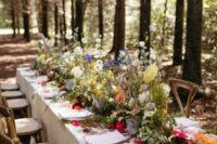 a gorgeous enchanted forest wedding tablescape with bright blooms, greenery and moss, clear chargers and neutral napkins