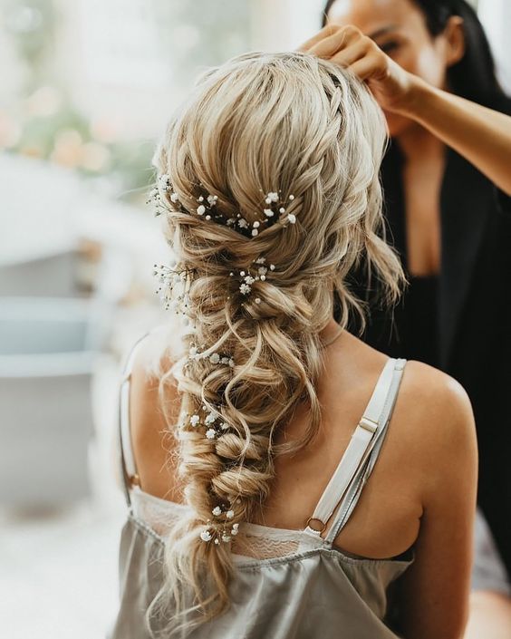 a gorgeous loose and messy twisted braid with a couple of braided halos and baby's breath tucked into the braid