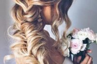 a gorgeous messy and loose fishtail braid with some waves and wavy locks framing the face is amazing