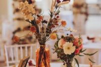 a lovely eclectic wedding centerpiece of a wood slice, neutral and bold dried blooms and greenery, candles and photos is cool