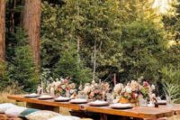 a lovely rustic enchanted forest wedding reception with wooden benches and a table, bright blooms and pink candles is amazing