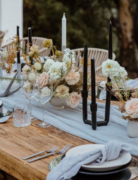 a luxury modern micro wedding tablescape with a grey runner and napkins, black pipe candleholders and black candles, pastel florals