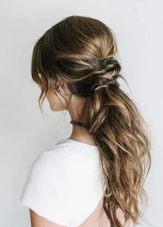 a messy low ponytail with a twsited part and some locks down is idea for hair with lowlights, a comfy modern hairstyle