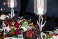 a super bold and refined fall enchanted forest wedding tablescape with a grass runner, dark foliage, bright berries, greenery, antler candleholders