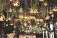 a unique indoor enchanting forest wedding reception space with evergreens hanging down and candles in bubbles is wow