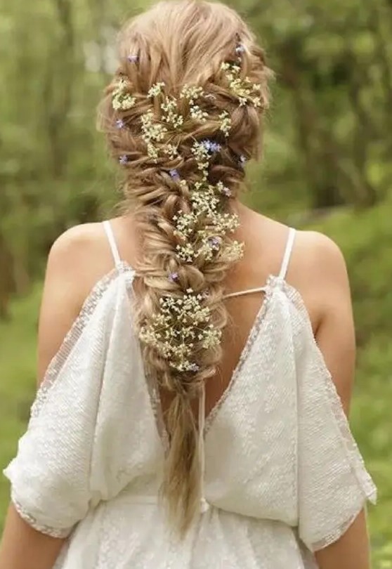a voluminous twisted braid with white and blue flowers tucked in will be a nice solution for a spring or summer boho bride
