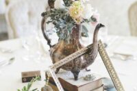 an eclectic vintage wedding centerpiece of a book stack, a vintage teapot with pastel blooms, a succulent in a mug