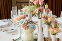 an eclectic vintage wedding centerpiece of book stacks, white vases with pastel blooms and a jar with pastel fabric flowers