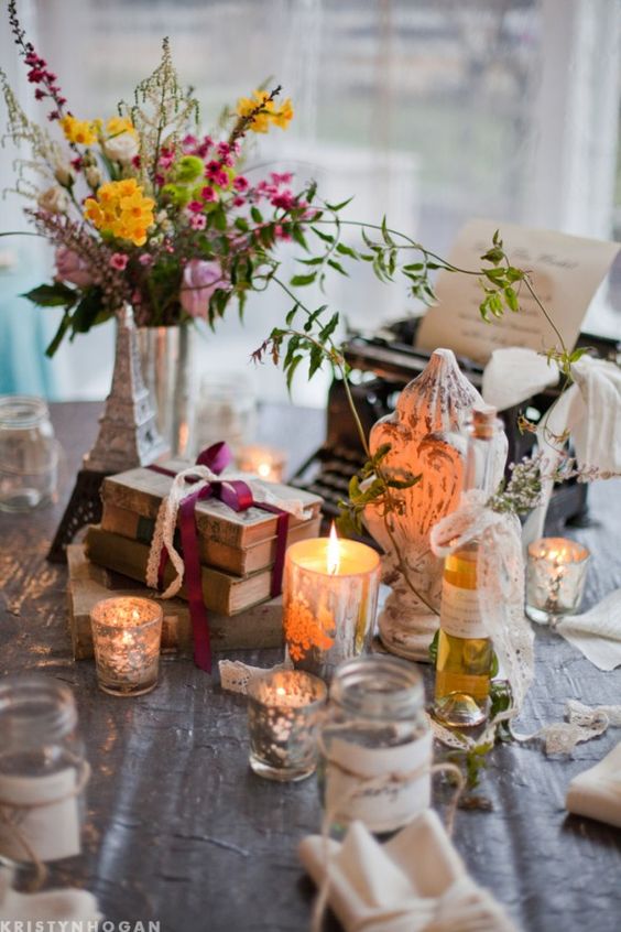 an eclectic vintage wedding centerpiece of candleholders, a vase with bright blooms and greenery, shabby chic decor