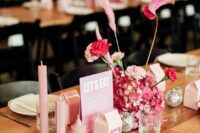 an eclectic wedding centerpiece of a cool pink flower arrangement, pink pillar candles, silver disco balls is amazing
