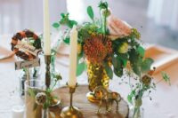 an eclectic wedding centerpiece of a tree slice, talll and thin candles, flower and greenery arrangements, small candles
