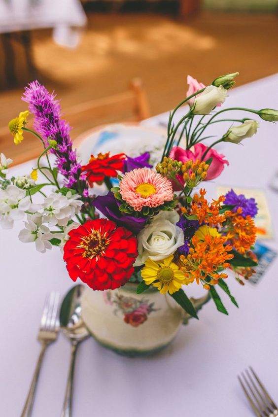 an eclectic wedding centerpiece of a vintage teapot and super bright blooms and greenery is amazing for a bold vintage wedding