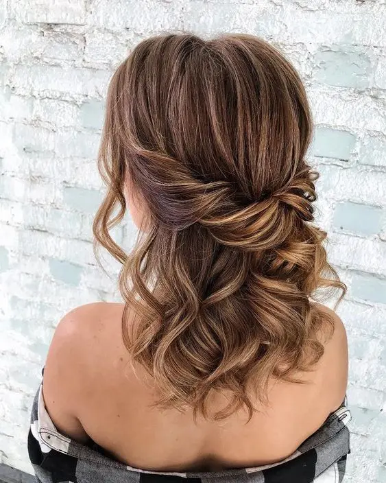 an elegant brown half updo with caramel balayage and a twisted touch plus some waves down and face framing locks