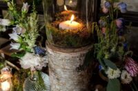 an enchanted forest wedding tablescape with a tree stump as a candleholder, moss, wildflowers and greenery, a burlap tablecloth and candles