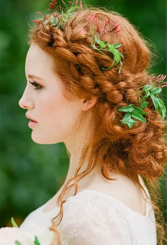 a boho messy braided low updo with fresh leaves tucked in and some locks down for a forest or fairytale bride