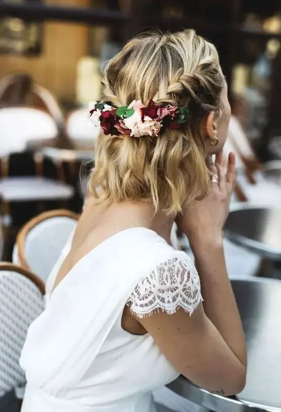 a wavy half updo with braids and a bit of blooms and greenery added to the hairstyle is a chic solution to rock