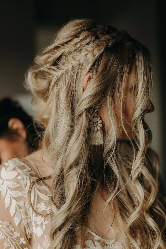 a boho wedding half updo with a double braided halo and waves down is a messy and cool hairdo for a wedding