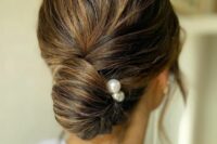 13 an elegant twisted low chingon with a volume on top and some pearl hair pins is classic for a wedding