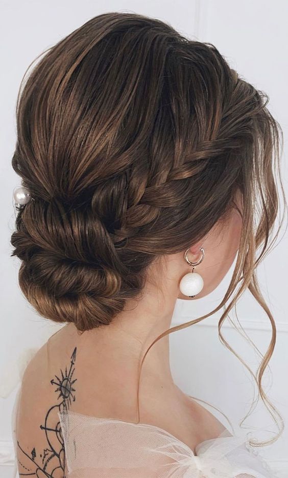 a cool twisted low updo with a braided halo, a bump on top and some locks framing the face is an elegant idea