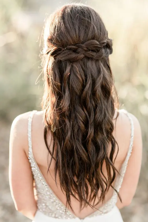 a braided half up half down hairstyle with a Dutch braid accent, waves down is a cool and chic idea for a boho bride