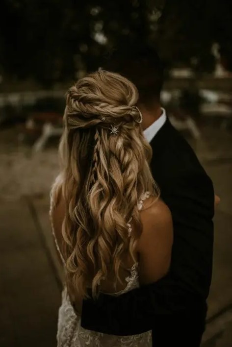 a celestial wedding half updo with a twisted and French braid halo, with a messy volume on top and waves and braids down plus celestial hair pins