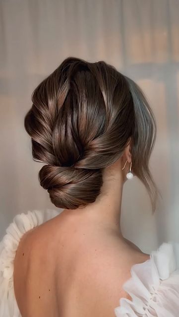 a glam and refined twisted low bun with a twisted top and some locks framing the face for a formal wedding