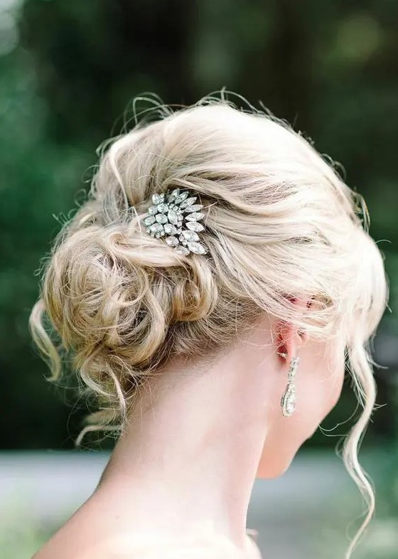 a messy curly updo for medium length hair with a rhinestone hairpiece and some locks framing the face is amazing