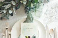 24 a gorgeous wedding tablescape with greenery and blooms, neutral porcelain, a sage green napkin, some chic cutlery and candles