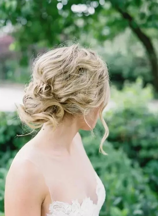 a messy wavy and twisted updo for an effortlessly chic bride, such an updo can be worn with long or medium length hair