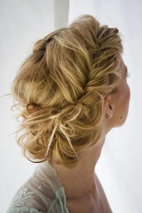A messy low updo with large braids and a messy volume on top is a gorgeous idea for a boho or just relaxed laid back bride
