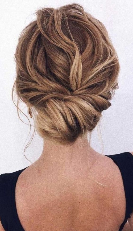 a messy twisted low bun with a messy top and some locks down is a stylish and chic idea for a not too formal bridal look