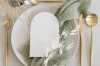 29 a modern rustic wedding tablescape with a neutral tablecloth, neutral porcelain, a sage green napkin and some dried herbs