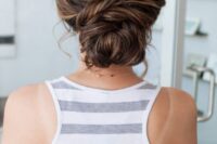 30 a pretty and a bit messy twisted low bun with a bump on top and some balayage is a chic and cool idea for a wedding