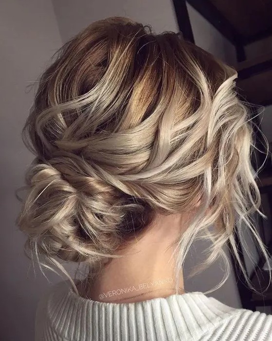 a super messy and wavy low bun with a bump and some locks down for a effortless look