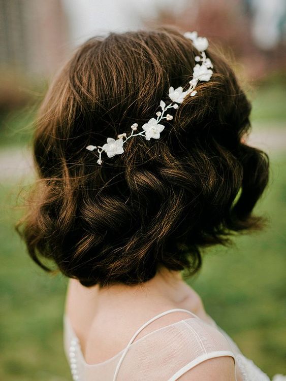 a wavy long dark brown bob with a bump on top and a delicate white floral hair vine is a very chic idea