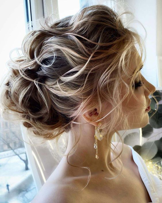 a wavy updo with a low chignon, a wavy volume on top and some locks down is a chic and cool idea for a wedding