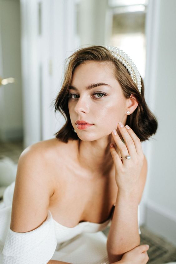 a brown wavy bob accented with a pearl headband is a very stylish and cool idea for a wedding