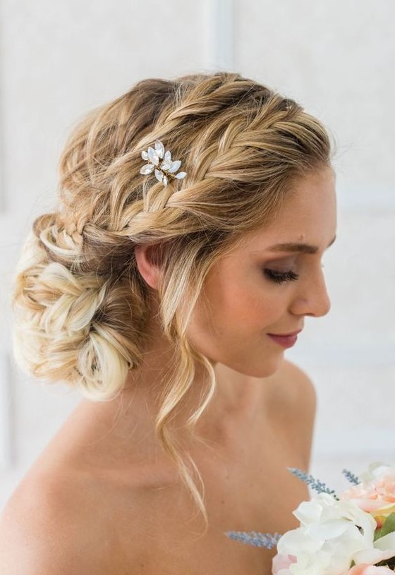 a romantic braided side chignon with several braids on top, some waves down and a crystal hairpiece