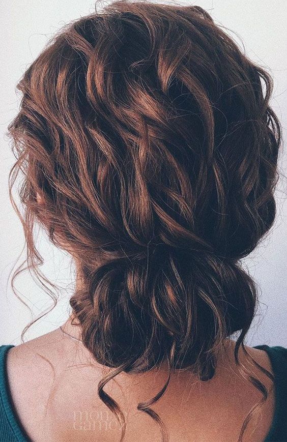 a wavy messy low updo with a wavy top and some locks down is a chic and cool idea for a wedding