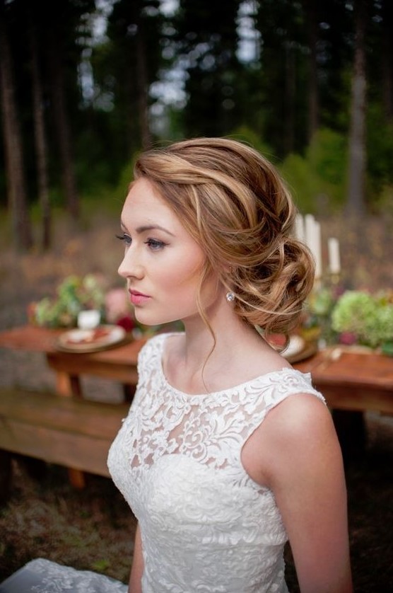 a stylish messy twisted low bun with a messy textural top and somw waves down is a cool idea of a wedding hairstyle