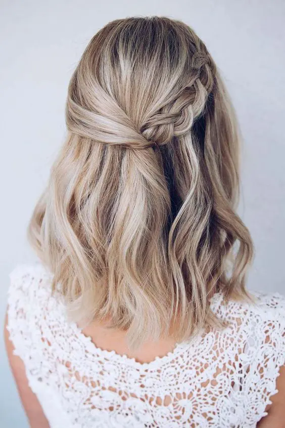a pretty wedding half updo with a twisted and braided halo and waves down is ideal for medium length hair